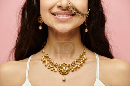 Une jeune femme indienne avec des bijoux en or et un anneau de nez posant élégamment