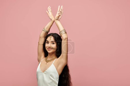 A young indian woman striking a pose in front of a vibrant pink background.
