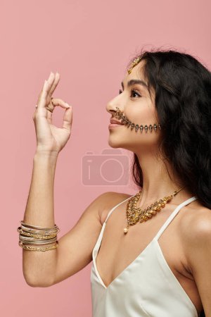 Junge Indianerin zeigt Goldschmuck mit Handgeste.