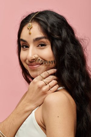 Young indian woman with nose ring striking a pose against pink backdrop.