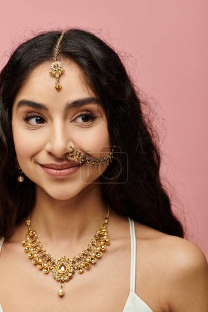 A stunning indian woman confidently showcases her gold necklace and earrings.
