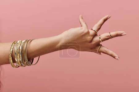 femme indienne présentant des bracelets en or sur sa main dans une pose élégante.