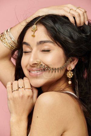 Mujer india joven con el pelo largo y joyas de oro golpeando una pose.