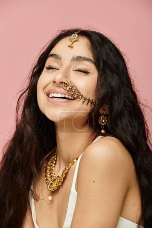 Smiling indian woman with long hair and gold jewelry.