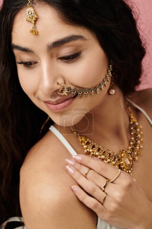 A captivating young indian woman showcases her elegant gold jewelry and nose ring.