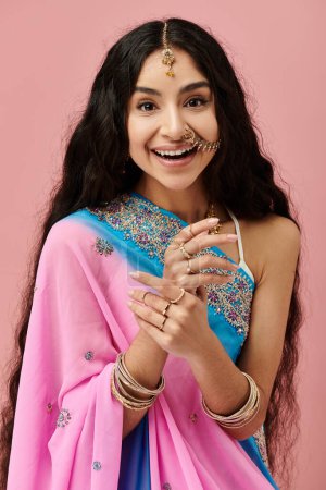 Smiling indian woman in vibrant sari poses happily.