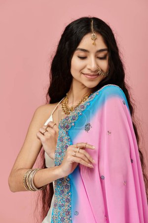 Young indian woman in vibrant sari poses elegantly.