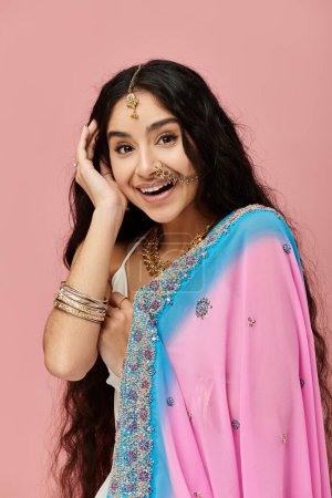 Young indian woman in pink and blue sari gracefully poses for a portrait.