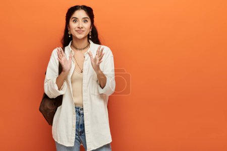Mujer india vibrante gesticulando enérgicamente sobre fondo naranja