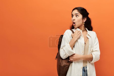 Photo for Young indian woman with backpack stands against vivid orange background. - Royalty Free Image