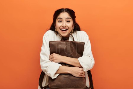 Young indian woman happily holding a brown backpack.
