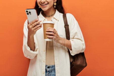 mujer india multitarea con café y teléfono en la mano.