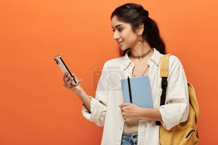 Photo for Young indian woman holding backpack, checking phone. - Royalty Free Image