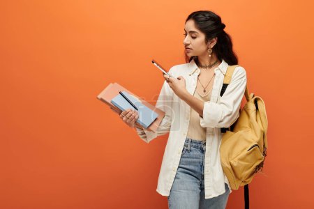 Active young indian woman holding a notebook and backpack.