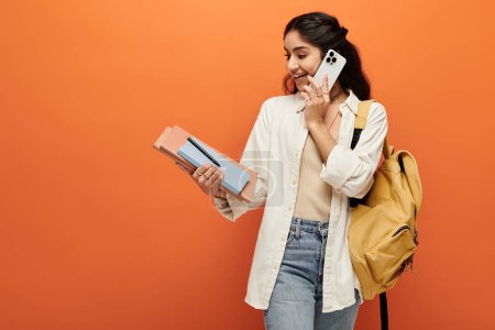 Photo for Young indian woman engaging in a phone call while carrying a backpack. - Royalty Free Image