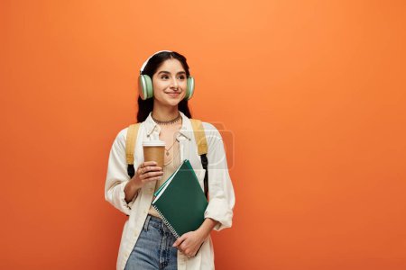 Young indian woman, headphones on, jotting notes in a notebook.