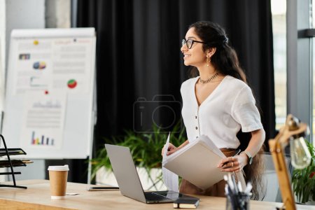Photo for Young indian woman in glasses working at desk with laptop. - Royalty Free Image