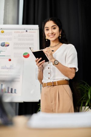 A young indian woman poses in front of a white board.