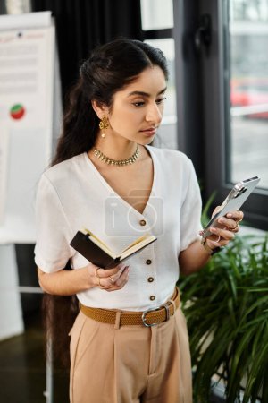 Businessindian woman concentrates on smartphone in office setting.