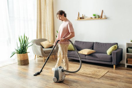 Man using vacuum cleaner in a stylish living room.