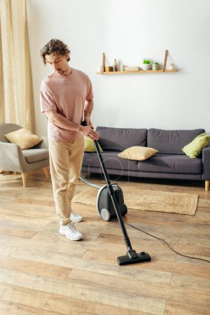 A man in cozy homewear vacuums the living room floor.