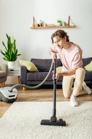 A handsome man in cozy homewear diligently vacuums the living room floor.