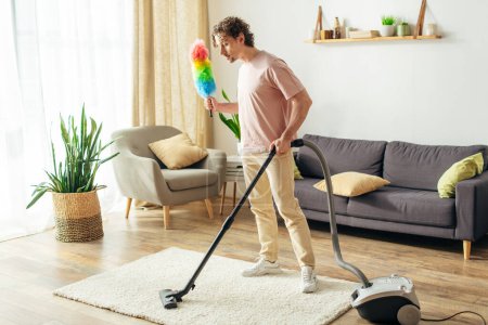 Un hombre en acogedora ropa de casa limpia la sala de estar con un vacío.