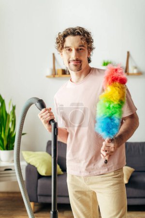Handsome man in cozy homewear holding a colorful toy while vacuuming.