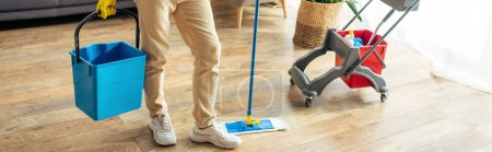 Foto de A man in cozy homewear mops the floor diligently. - Imagen libre de derechos