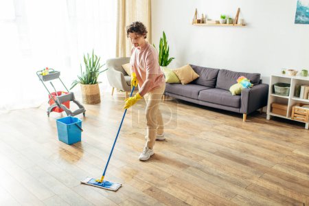 Photo for A man diligently cleans the floor with a mop in a brightly lit room. - Royalty Free Image