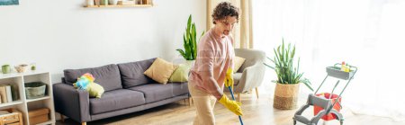 A man in a bright room cleans the floor with a mop.