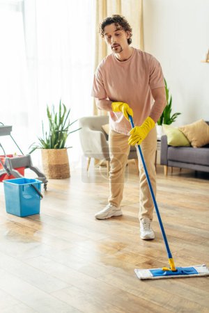 Téléchargez les photos : Bel homme dans confortable vêtements de maison nettoyer le sol. - en image libre de droit