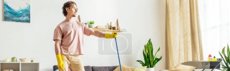 A man in cozy homewear mopping the living room floor.