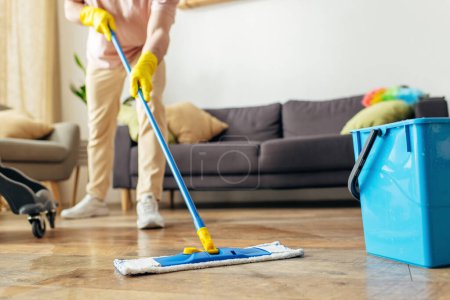 Mann in Hauskleidung reinigt Fußboden mit Wischmopp.