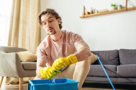 A handsome man in cozy homewear diligently cleans the floor with a mop.