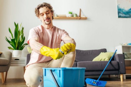 Foto de Un hombre guapo en ropa de casa limpia el suelo con una fregona. - Imagen libre de derechos