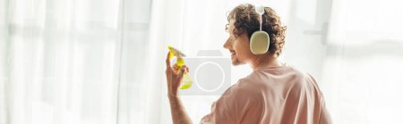 Photo for A man in a pink shirt is holding a yellow spray. - Royalty Free Image