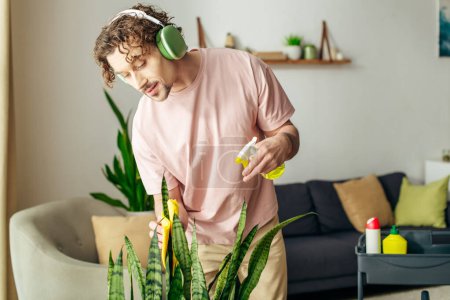 Stylish man in a pink shirt listens to music near a green plant.