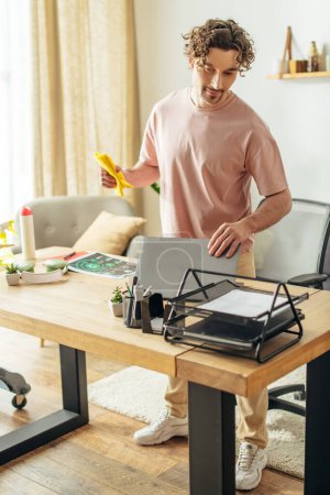 Un hombre en ropa de casa acogedora está delante de una mesa con un ordenador portátil en ella.