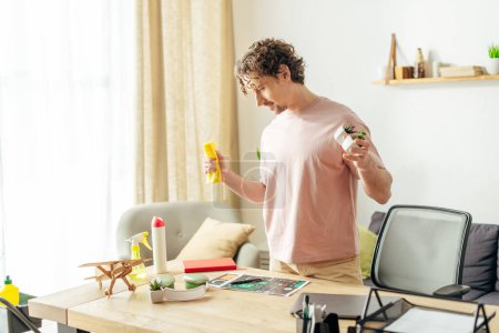 Hombre guapo en ropa de casa acogedora sosteniendo un spray en una sala de estar.