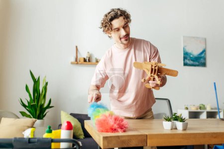 Ein Mann in kuscheliger Hauskleidung spielt mit einem Spielzeugflugzeug aus Holz.