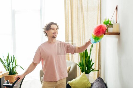 Hombre guapo en ropa de casa acogedora sosteniendo un colorido plumero.