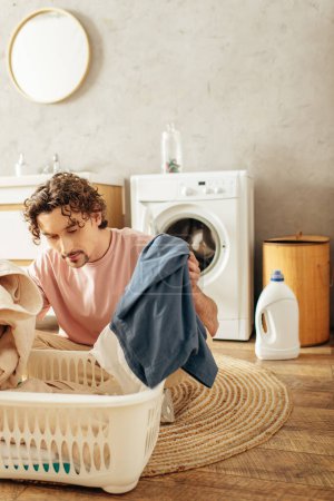 A handsome man in cozy homewear doing laundry in a laundry basket.