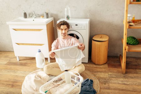 Jeune homme hypnotisé par la machine à laver.