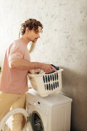 Ein Mann in kuscheliger Hauskleidung lädt einen Wäschekorb auf eine Waschmaschine.