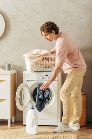 A handsome man in cozy homewear stands next to a washing machine, ready to clean his house.
