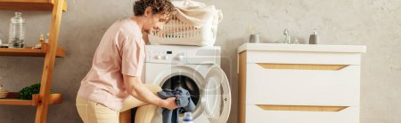 Photo for A man carefully loading clothes into a washing machine. - Royalty Free Image