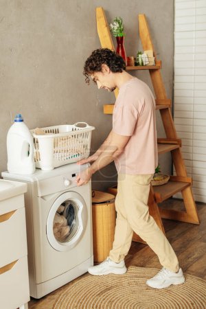 A man in cozy homewear loading a washing machine.