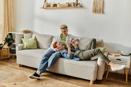 Zwei Frauen, ein lesbisches Paar mit kurzen Haaren, sitzen gemütlich auf einer Couch in einem gemütlichen Wohnzimmer.
