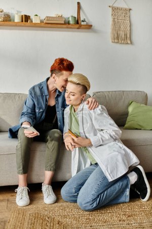 Two women with short hair relax on a cozy couch in a living room.